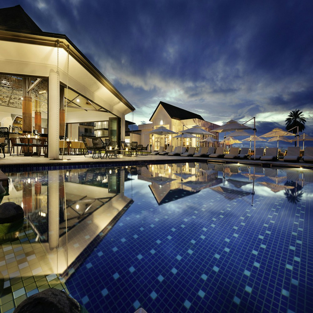 Hotel iluminado à noite com piscina e arquitetura acolhedora